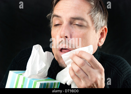 Portrait d'un homme sur le point de l'éternuement d'un produit désinfectant et la boîte. Banque D'Images