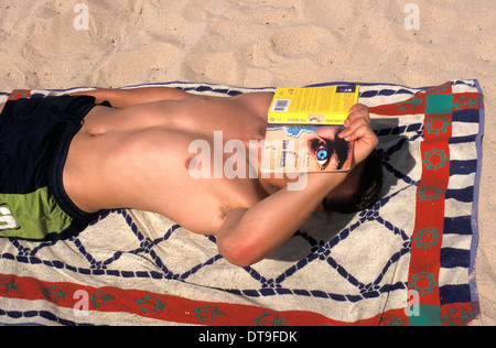 Vacancier de lire un livre, la plage tout en bronzant à San Antonio, Ibiza, Espagne Banque D'Images