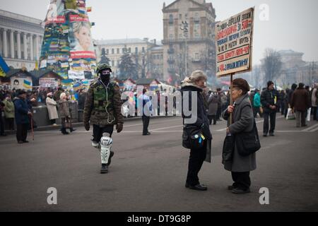 Kiev, Ukraine. 12 Février, 2014. Un manifestant anti habillés en costume de l'armée marche par deux femmes sur la place de l'indépendance le 12 février 2014. La Russie va lancer le prochain versement de la somme de 15 milliards de dollars de prêt à l'Ukraine à la fin du mois, un journal proche du Président Viktor Ianoukovitch a déclaré le 10 février, à la suite de pourparlers entre le chef de l'Ukraine et son homologue russe. Photo par Emeric Fohlen/NurPhoto Crédit : Emeric Fohlen/NurPhoto ZUMAPRESS.com/Alamy/Live News Banque D'Images