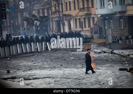 Kiev, Ukraine. 12 Février, 2014. Un prêtre prie entre manifestants et policiers sur les lieux de manifestations anti-gouvernementales près de Dynamo Stadium le 12 février 2014 à Kiev, Ukraine. De violentes manifestations en Ukraine se sont répandues au-delà de la capitale que le Président Viktor Ianoukovitch a tenu une réunion de crise avec les trois principaux dirigeants de l'opposition. Photo par Emeric Fohlen/NurPhoto Crédit : Emeric Fohlen/NurPhoto ZUMAPRESS.com/Alamy/Live News Banque D'Images