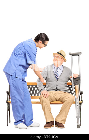 Professionnel de santé masculins senior aide un homme assis sur un banc Banque D'Images