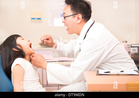 Petite fille ayant la gorge avec l'examen clinique à l'abaisse-langue Banque D'Images