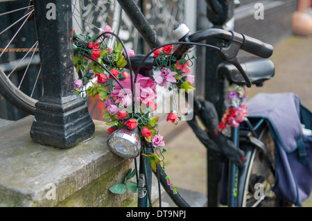 Old Fashioned ou Vintage vélo ou Bicycle décorées avec des fleurs roses près de Canal House à Amsterdam Banque D'Images