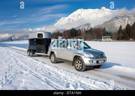 Quatre roues motrices véhicule tractant une remorque pour cheval sur une route couverte de neige dans les montagnes du Nord, Gnadenwald, Tyrol, Autriche Banque D'Images