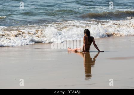 Une jeune femme portant bikini est assis dans le sable de plage d'Anjuna, plage, Inde Banque D'Images