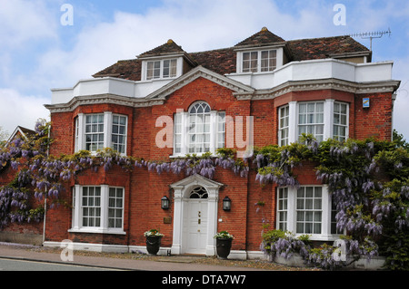 Wisteria floribunda croissant sur une maison géorgienne à Lavenham, Suffolk. Banque D'Images