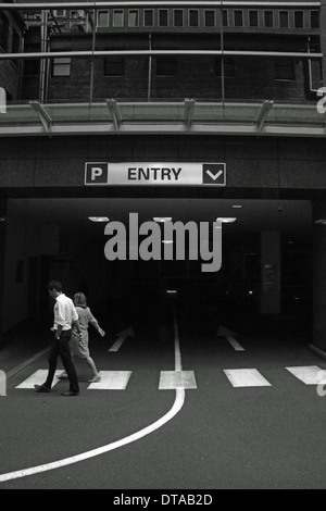 Architecture noir et blanc et des gens d'affaires marcher avec un parking et l'entrée du parking à proximité signe. Capturé à Melbourne, Australie. Banque D'Images