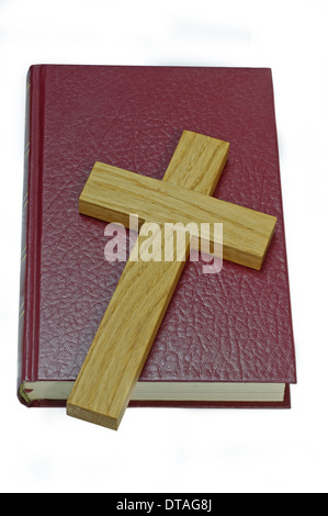 Croix en bois couché sur une vieille Bible en cuir rouge. Isolé Banque D'Images