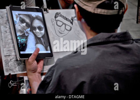 Artiste de rue utilisant une image d'ordinateur de tablette iPad pour dessiner son portrait de sujets. Thaïlande S. E. Asie. Banque D'Images