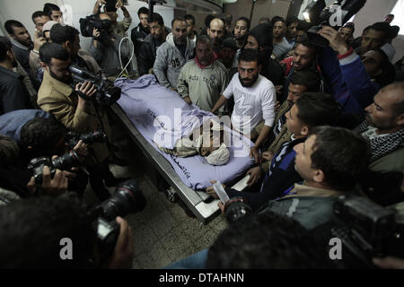 La bande de Gaza. Feb 13, 2014. Les Palestiniens se rassemblent autour du corps d'Ibrahim Mansour dans un hôpital de la ville de Gaza le 13 février 2014. Un Palestinien a été tué jeudi dans les balles israéliennes près de la frontière entre le Hamas et Israël et la bande de Gaza, les medecins a dit. Des soldats israéliens ont ouvert le feu sur un groupe de travailleurs qui ont été la collecte de gravier près de la clôture, en tuant un et en blessant un autre, selon les sources. Credit : Wissam Nassar/Xinhua/Alamy Live News Banque D'Images