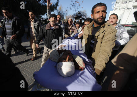 La bande de Gaza. Feb 13, 2014. Les Palestiniens se déplacer le corps d'Ibrahim Mansour de l'avant dans un hôpital de la ville de Gaza le 13 février 2014. Un Palestinien a été tué jeudi dans les balles israéliennes près de la frontière entre le Hamas et Israël et la bande de Gaza, les medecins a dit. Des soldats israéliens ont ouvert le feu sur un groupe de travailleurs qui ont été la collecte de gravier près de la clôture, en tuant un et en blessant un autre, selon les sources. Credit : Wissam Nassar/Xinhua/Alamy Live News Banque D'Images