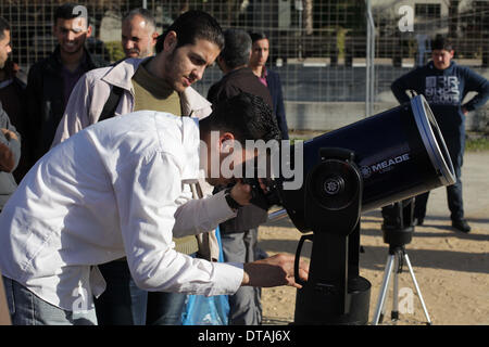 La ville de Gaza, bande de Gaza, territoire palestinien. Feb 13, 2014. Un étudiant palestinien regarde à travers un télescope vers le soleil au cours d'une formation pratique pour identifier l'astronome de taches de couleur et son impact, dans la ville de Gaza le 13 février 2014 Credit : Ashraf Amra/APA Images/ZUMAPRESS.com/Alamy Live News Banque D'Images