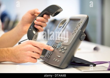 Close-up of woman mains prendre le téléphone de l'hameçon, in office Banque D'Images