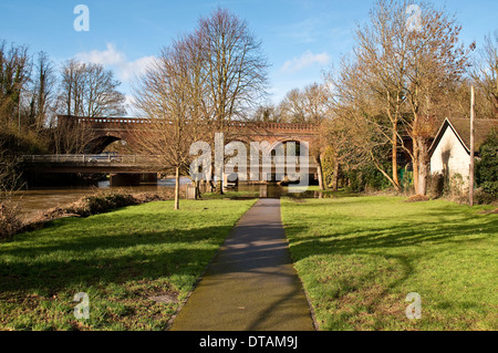 Chemin le long de la rivière Mole menant à l'époque victorienne pont de chemin de fer et le pont routier moderne, Leatherhead, Surrey, England, UK Banque D'Images