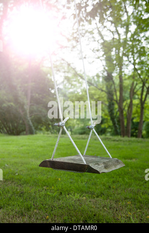 Une balançoire en bois dans un jardin pittoresque. La lumière du soleil des reflets. Banque D'Images