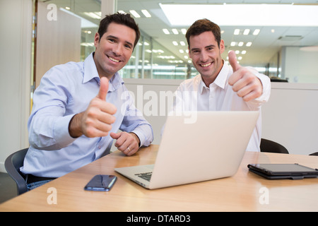 Succès smiling businessmen in office, à la caméra, giving Thumbs up Banque D'Images