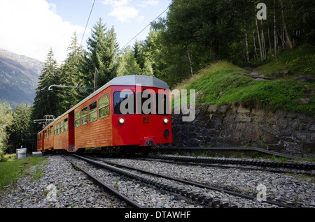 Un train rouge et blanc du train à crémaillère du Montenvers grimpe dans les arbres au-dessus de Chamonix en France. Banque D'Images