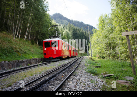 Un train rouge et blanc du train à crémaillère du Montenvers grimpe dans les arbres au-dessus de Chamonix en France. Banque D'Images