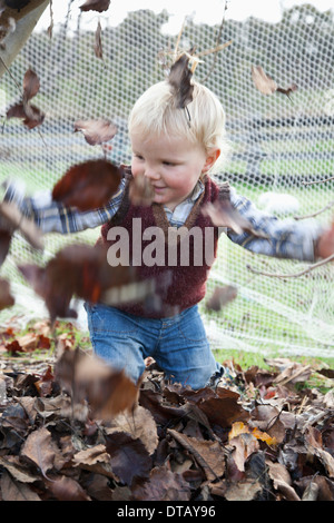 Bébé garçon en train de lancer des feuilles sèches Banque D'Images