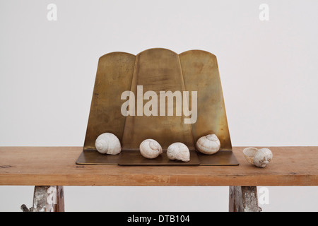 Coquilles d'escargots et des pièces de métal sur un workbench Banque D'Images