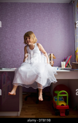 Portrait of Girl sitting on table Banque D'Images