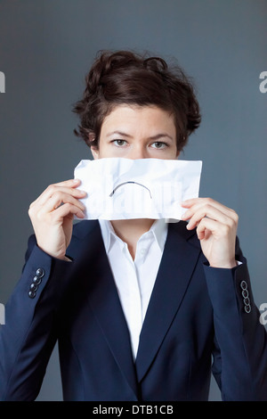 Portrait of mid adult woman holding paper avec froncement, close-up Banque D'Images