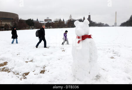 Washington DC, USA. Feb 13, 2014. Les gens passe devant un bonhomme en face du monument national sur le National Mall à Washington DC, capitale des États-Unis, le 13 février 2014. La tempête de l'hiver aux États-Unis d'états du sud a apporté beaucoup de neige et de grésil de congélation pour le nord-est le jeudi, la fermeture des agences fédérales, les écoles et les aéroports tout en laissant un demi-million de personnes sans électricité. La neige et la glace a rendent les déplacements difficiles pour les navetteurs dans le centre-ville de D.C. zone comme le gouvernement local a exhorté les résidents à rester à l'intérieur et de la routes dangereuses. Banque D'Images