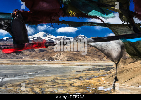 Le lac Yamdrok congelé et Mt Nojin Kangtsang (7191m) vu à travers les drapeaux de prières dans Tsang, Tibet Banque D'Images