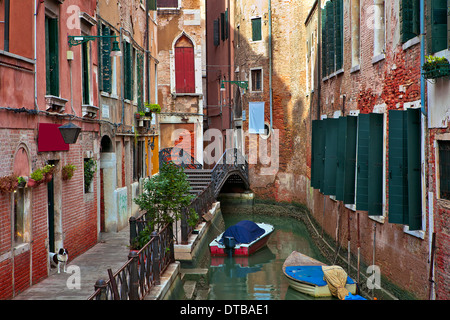 Bateaux sur canal étroit entre les vieilles maisons typiques avec des murs en brique rouge de Venise, Italie. Banque D'Images