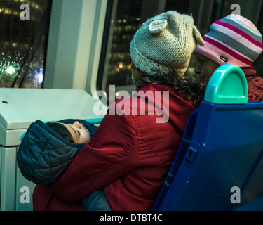 Sur le chemin du retour - fatigué enfant endormi avec deux femmes sur le DLR (Docklands Light Railway) - Londres, Royaume-Uni Banque D'Images