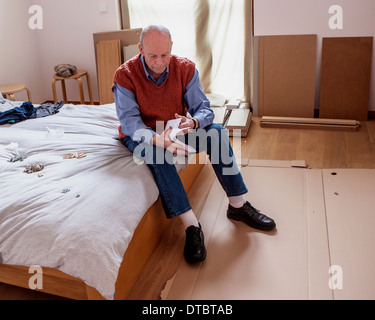 Senior man reading instructions d'assemblage de meubles Ikea flatpack Banque D'Images