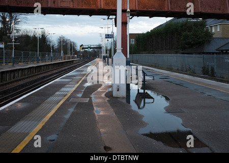 La plate-forme de la gare de Twickenham déserte tôt le matin avec les postes, les piscines d'eau de pluie et passage supérieur, London, UK Banque D'Images