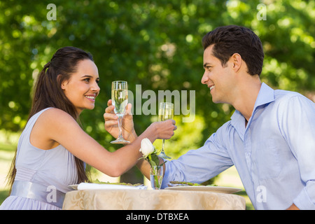 Couple avec des flûtes à champagne sitting at outdoor cafÃ© Banque D'Images