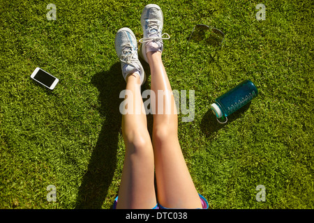 Les jambes de la jeune femme sur l'herbe ensoleillée dans park Banque D'Images