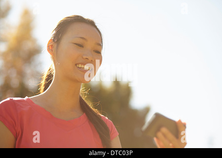 Young woman in park looking at mobile phone Banque D'Images