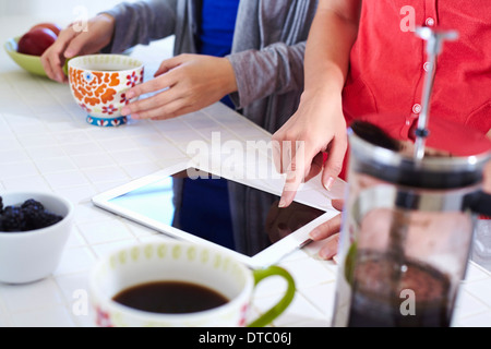 Deux jeunes femmes dans la cuisine using digital tablet tandis que le café Banque D'Images