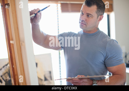 Mâle mature artiste travaillant sur toile en studio Banque D'Images