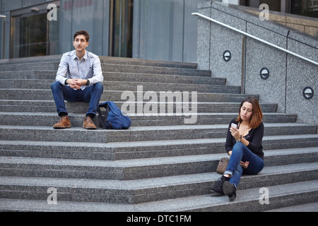 Malheureux couple sitting on steps apart Banque D'Images