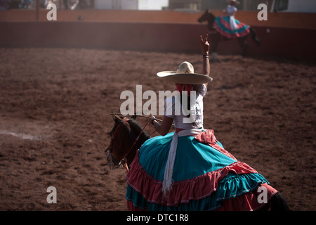 Un escaramuza faire un signe à son équipe bien que concurrentes dans un Escaramuza dans le Lienzo Charros el Penon, Mexico City Banque D'Images