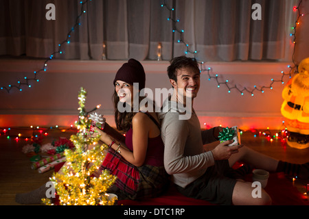 Jeune couple l'échange de cadeaux à Noël dans la salle de séjour Banque D'Images