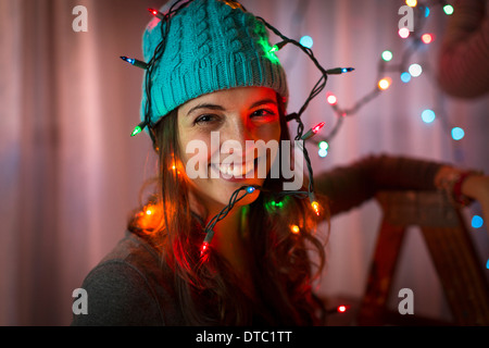 Portrait de jeune femme enveloppée dans les lumières de Noël Banque D'Images