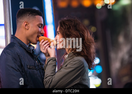 Jeune couple de touristes partageant hotdog, New York City, USA Banque D'Images