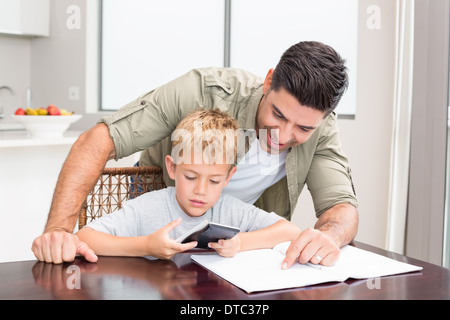 Smiling father helping son avec des devoirs de mathématiques à table Banque D'Images