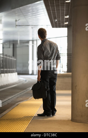 Young office worker regarder à la station de train Banque D'Images