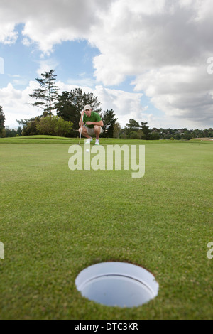 Young male golfer alignant la balle sur le green Banque D'Images