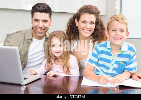 Heureux parents et à colorier à l'aide d'un ordinateur portable avec leurs jeunes enfants Banque D'Images