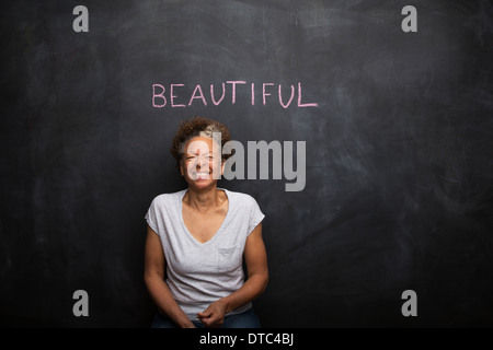 Senior woman in front of blackboard et le mot belle Banque D'Images