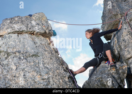 Young female rock climber sitting on rock ledge Banque D'Images