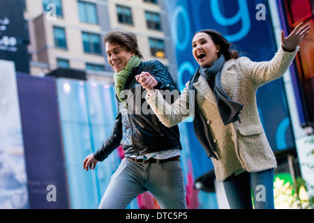 Jeune couple d'exécution sur street, New York City, USA Banque D'Images