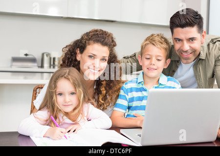 Heureux parents et à colorier à l'aide d'un ordinateur portable avec leurs enfants Banque D'Images